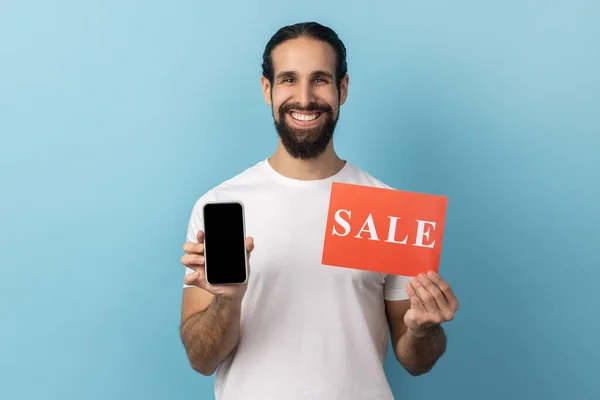 Sakallı Beyaz Tişörtlü Elinde Satış Kartı Akıllı Telefon Olan Yakışıklı — Stok fotoğraf
