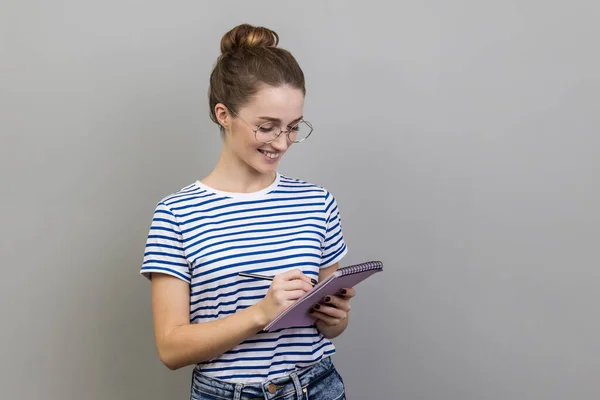 티셔츠를 안경을 영감받은 여성의 노트북에 아이디어를 계획을 세우고 은회색 배경에 — 스톡 사진