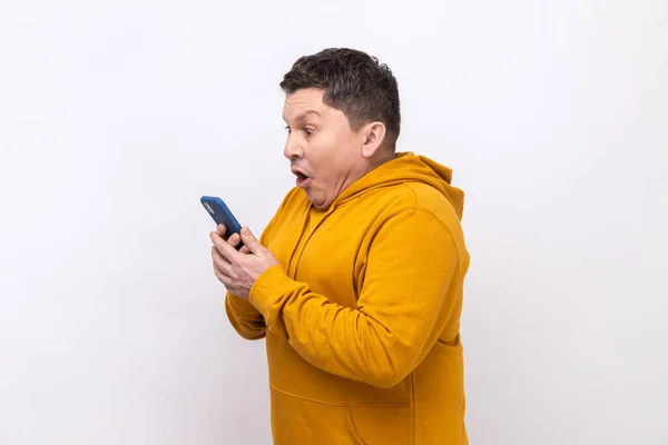 Widok Boku Człowieka Używającego Telefonu Komórkowego Zaskoczonym Wyrazem Twarzy Uzależnionego — Zdjęcie stockowe