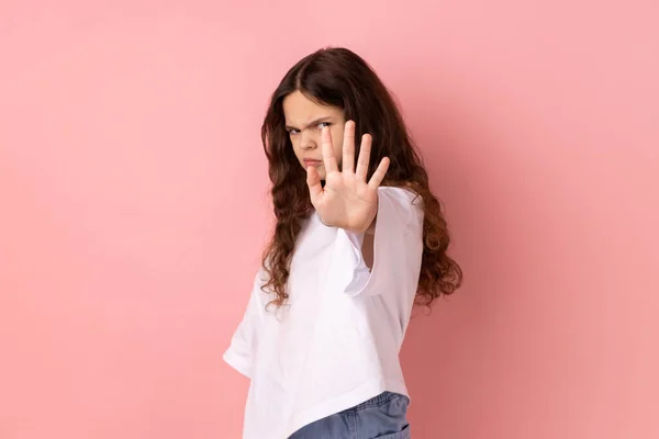 怒气冲冲的小女孩穿着白色T恤 用手掌向外做停止动作 表示否认或限制 肢体语言 在粉色背景下被隔离的室内拍摄 — 图库照片