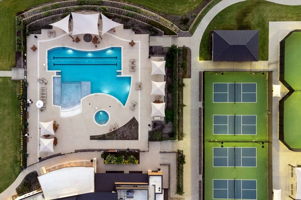 stock image Aerial view of large tennis courts, swimming pool at community recreational center with mansions with lounge areas in the summertime outdoor.