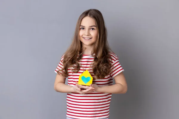 Portret Dziewczynki Pasiastej Koszulce Trzymającej Dłoniach Papierowy Domek Patrzącej Uśmiechem — Zdjęcie stockowe