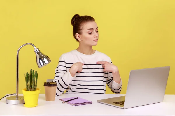 これは俺だ 自信のある利己的な女性労働者は自分自身を指して 傲慢な表情でノートパソコンの画面を見て オフィスで働いています 黄色の背景に隔離された屋内スタジオショット — ストック写真