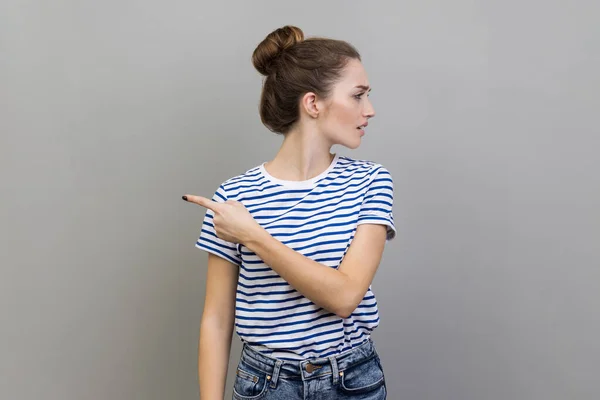 Get out. Portrait of woman annoyed young adult in striped T-shirt turning away and asking to leave her, showing exit, feeling betrayed and resentful. Indoor studio shot isolated on gray background.