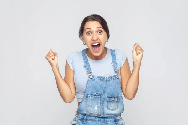 Champion Portrait Victorious Delighted Woman Wearing Denim Overalls Clenching Fists — Zdjęcie stockowe