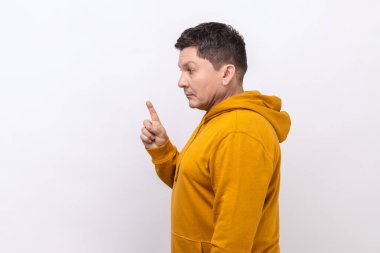 Side view of angry middle aged man scolding for mistake, dissatisfied with behavior, blaming showing admonishing gesture, wearing urban style hoodie. Indoor studio shot isolated on white background.