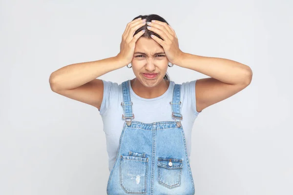 Depressed Woman Wearing Denim Overalls Frowning Clasping Sore Head Suffering — Stock fotografie