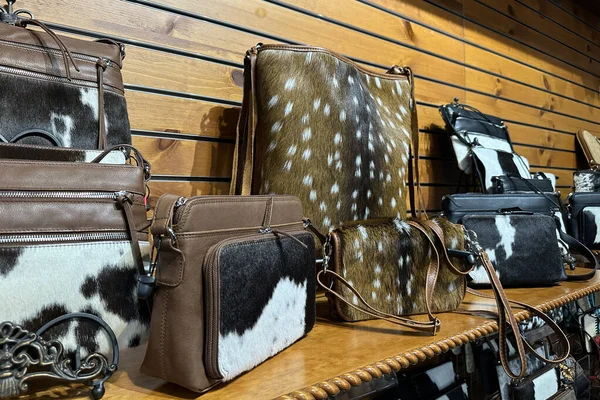 Collection of handmade leather cowboy bags on wooden shelf in store in texas.