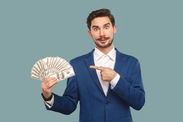 一个严肃而自豪的男人 留着胡子 站在那里指着钞票 拿着她的薪水 穿着白衬衫和夹克 室内拍摄被淡蓝色背景隔离 — 图库照片