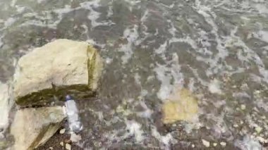 Sahile dökülen çöpler, kirli deniz kumlu kıyılar, çevre kirliliği, ekolojik sorunlar, arka planda hareket eden dalgalar.. 
