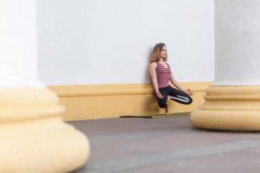 Atletik genç yetişkin sporu. Yogi kadın eğitmeni. Hatha yogası yapıyor. Beyaz duvarın yanında..