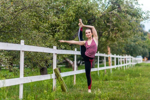 소녀의 초상화 다리를 늘이고 요가를 연습하고 야외에서 운동을 다리를 — 스톡 사진