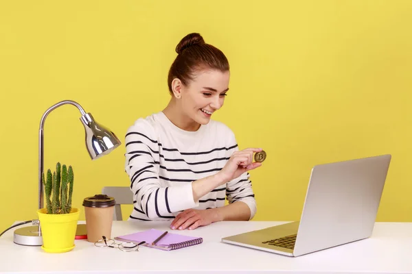 暗号通貨デジタルマネー 積極的な女性は オフィスの職場に座って ノートパソコンの画面に黄金のビットコインを示し 表示する笑顔 黄色の背景に隔離された屋内スタジオショット — ストック写真