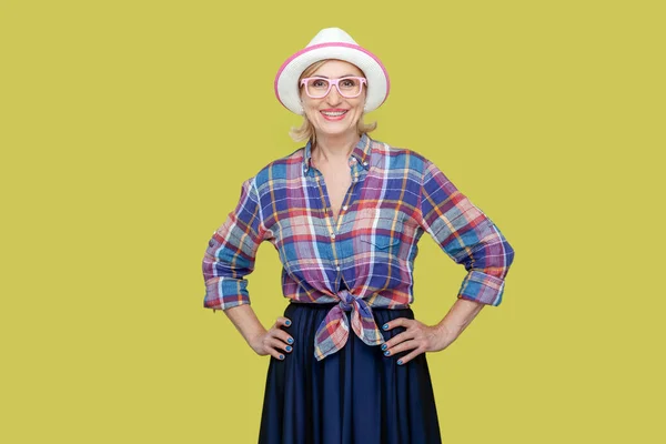 Radosna Optymistyczna Starsza Kobieta Szachownicowej Koszuli Kapeluszu Okularach Stojąca Rękami — Zdjęcie stockowe