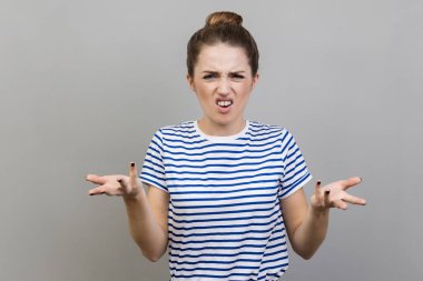 Sen ne istiyorsun? Çizgili tişört giyen bir kadının portresi bu çatışmayı neden yaptığını soruyor, kızgın bir ifadeyle bakıyor. Gri arka planda izole edilmiş kapalı stüdyo görüntüleri.