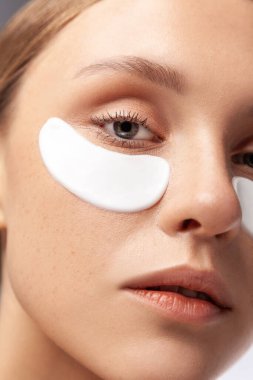 Yüzüne özen gösteren güzel bir kadın modelin yakın plan portresi hidrojenler, kozmetoloji rutini. Kapalı alanda çekilen çekim gri arka planda izole edildi.