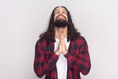 Çaresiz kırmızı gömlekli, merhamet dilenen, ağlayan, avuç içlerini bir arada tutan, bir şey için yalvaran umutsuz bir adam. Gri arka planda izole edilmiş kapalı stüdyo görüntüleri.