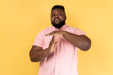 Zaman doldu. Pembe tişörtlü bir adamın portresi. Daha fazla zamana ihtiyacım var. Duraklat. Sarı arka planda kapalı stüdyo çekimleri.