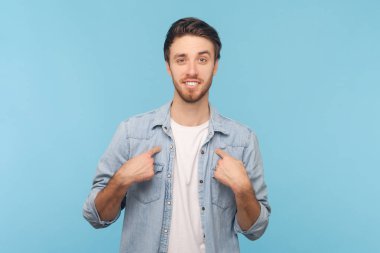 Üstesinden gelebilirim. Kararlı bir adam kendini işaret eder, gururlanır ve kendi başarılarıyla övünür, kot gömlek giyerek kendi yardımını teklif eder. Mavi arkaplanda kapalı çekim.