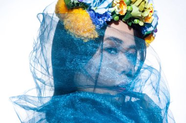 Yandan bakınca, güzel bir kadının portresi. Çiçekli şapkalı, mavi peçeli, yüzünü gizleyen, başka tarafa bakan güzel bir model. Gri arka planda izole edilmiş kapalı stüdyo görüntüleri.