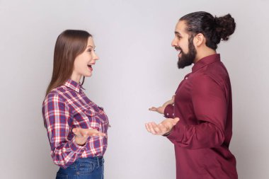 Heyecanlı iyimser kadın ve erkeğin el pençe divan duran portresi, birbirini görünce şaşıran, tanıştığımıza sevinen. Gri arka planda izole edilmiş kapalı stüdyo görüntüleri.