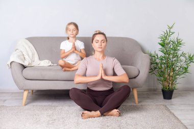 Farkındalık ve uyum. Lotus duruşu. Sakin bir kadın, gözleri kapalı, jest yaparak yoga yapıyor, nefes alma tekniği uyguluyor, odada meditasyon yapıyor, yerde oturuyor..
