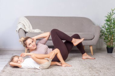 Güzel bir kadının mekik çekerken portresi, büyüleyici küçük kızıyla karın kasları üzerinde çalışırken, ailece evde spor yaparken..
