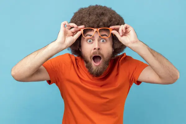 Sjokkert Overrasket Mann Med Afro Frisyre Iført Oransje Skjorte Stående stockbilde