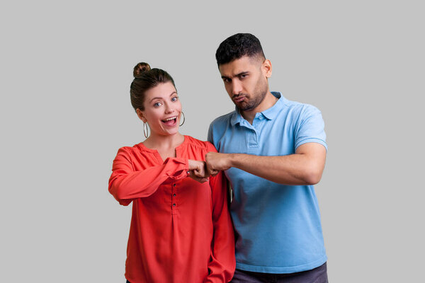 Портрет взволнованной семейной пары, стоящей вместе кулаком к кулаку хорошая работа в команде положительное выражение отличные компаньоны. Крытая студия, снятая на сером фоне.
