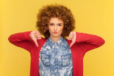 Afro saç stili değerlendirme projesi olan hoşnutsuz bir kadının portresi, hoşnutsuzluk belirtileri gösteriyor, olumsuz ifade ve hoşnutsuzlukla bakıyor. Sarı arka planda kapalı stüdyo çekimleri.