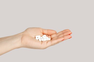 Bir avuç dolusu ilaç kapsülü, besin takviyesi, vitaminler, ilaçlar. Gri arka planda izole edilmiş kapalı stüdyo görüntüleri.