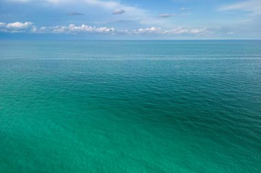 Dalgalanan dalgalı deniz dalgaları gökyüzünü yansıtır ve bulutlar soyut ve parlak yüzey oluşturur, Playa Miami Plajı