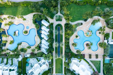 Berrak mavi havuzları ve bereketli palmiye ağaçları olan egzotik tatil beldesi manzarası güneşli tropikal manzarada lüks dış görünüşü Playa Miami Plajı