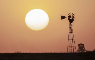 Turuncu gün batımında yel değirmeni, Pampas, Patagonya, Arjantin.