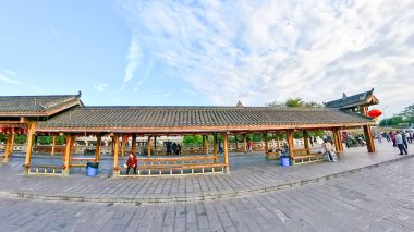 Çin, LeShan, 01.01.2025 eski Suji Çin kasabasında bulunan pagoda ile antik köprüyü geçen insanlar.