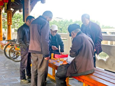 Çin, LeShan, 01.01.2025 yaşlılar eski şehirde sokak boyunca Çin satrancı oynuyorlar.