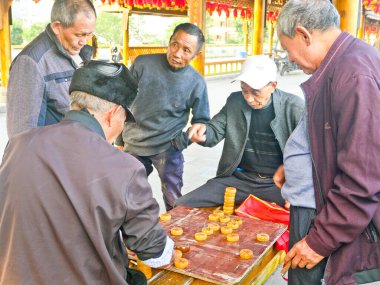 Çin, LeShan, 01.01.2025 yaşlılar eski şehirde sokak boyunca Çin satrancı oynuyorlar.