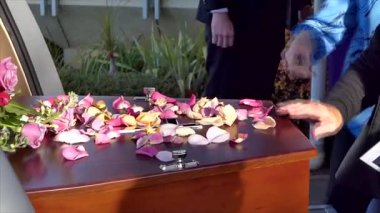 Aile, cenaze töreninden sonra tabutun içine çiçek yaprakları yerleştiriyor.