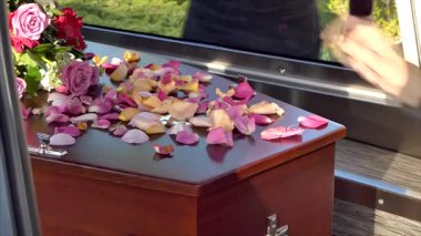 Aile, cenaze töreninden sonra tabutun içine çiçek yaprakları yerleştiriyor.