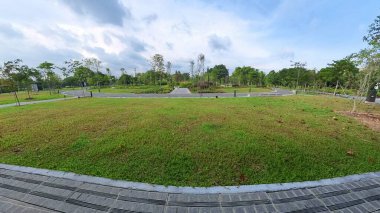 Singapur Çin Bahçesi. Genç ağaçlarla, yeşilliklerle, dolambaçlı yollarla ve bulutlu gökyüzüyle sakin ve doğal bir atmosfer yaratan manzaralı bir park. 