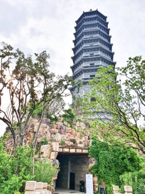 Uzun, süslü bir pagoda geleneksel çatıların üzerinde yükseliyor ve parlak bir gökyüzü altında yemyeşil, huzuru ve tarihi güzelliği simgeliyor.. 