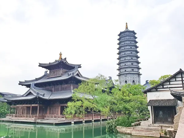 Uzun, süslü bir pagoda geleneksel çatıların üzerinde yükseliyor ve parlak bir gökyüzü altında yemyeşil, huzuru ve tarihi güzelliği simgeliyor.. 