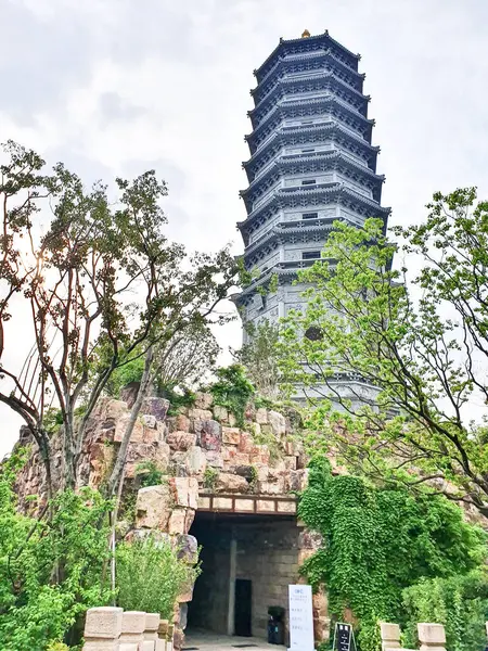 Uzun, süslü bir pagoda geleneksel çatıların üzerinde yükseliyor ve parlak bir gökyüzü altında yemyeşil, huzuru ve tarihi güzelliği simgeliyor.. 