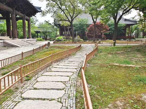 Yeşil bir göl kenarında huzurlu bir taş yol geleneksel bir Çin tapınağına ve bulutlu bir gökyüzünün altındaki tapınağa götürür. 