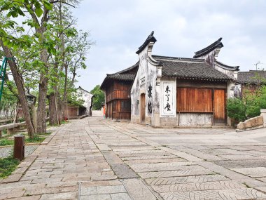 Taş duvarları, fenerleri, ağaçları ve binaları olan sakin geleneksel bir Çin sokağı.