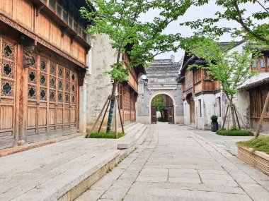 Taş duvarları, fenerleri, ağaçları ve binaları olan sakin geleneksel bir Çin sokağı.