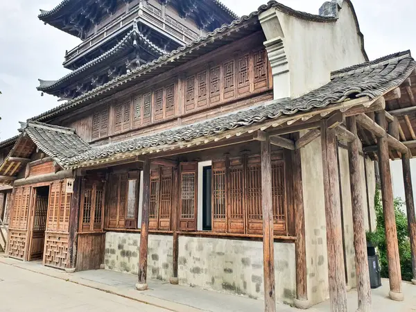 Geleneksel Çin ahşap binası, karmaşık kafes camları, katmanlı çatı tasarımı ve kırsal sütunları sessiz bir yürüyüş yolu boyunca duruyor. 