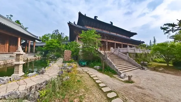 Geleneksel Çin ahşap binası, karmaşık kafes camları, katmanlı çatı tasarımı ve kırsal sütunları sessiz bir yürüyüş yolu boyunca duruyor. 