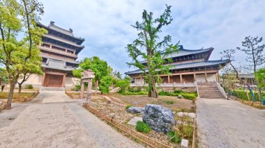Görkemli, çok katmanlı ahşap bir tapınak. Karmaşık çatı sahaları ve geleneksel oymalar bulutlu bir arka planda duruyor. 
