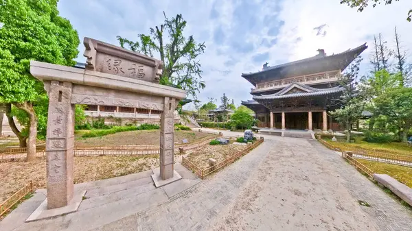 Görkemli, çok katmanlı ahşap bir tapınak. Karmaşık çatı sahaları ve geleneksel oymalar bulutlu bir arka planda duruyor. 